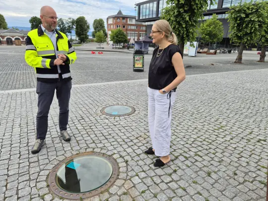 Administrerende direktør i Hias Knut Holen sammen med fungerende ordfører Jane Meyer i Hamar ved de gjennomsiktige kumlokkene på Stortorget.